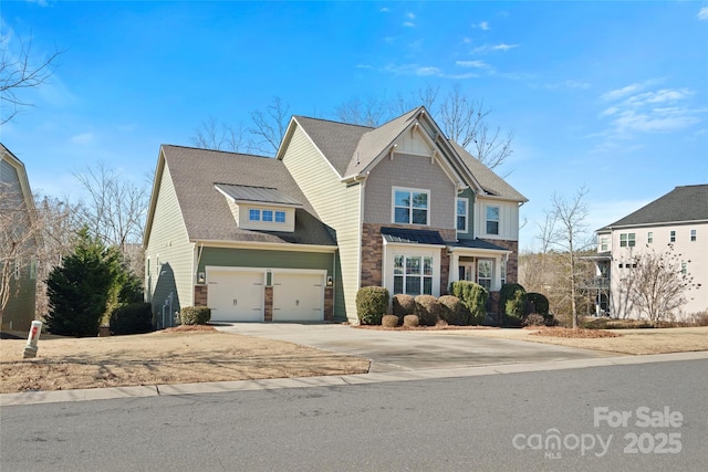 view of front of home with stone siding, a garage, and driveway