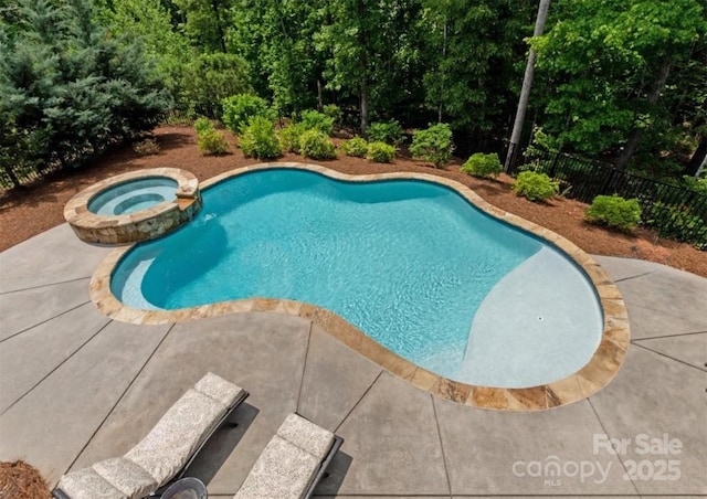 view of swimming pool with a patio, fence, and a pool with connected hot tub