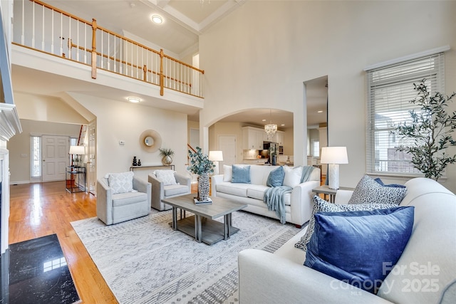 living room featuring wood-type flooring, a wealth of natural light, a high ceiling, and a chandelier