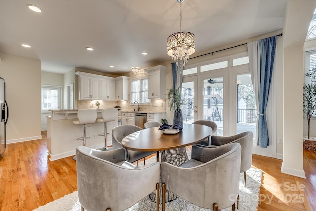 dining room featuring sink, light hardwood / wood-style floors, and a notable chandelier