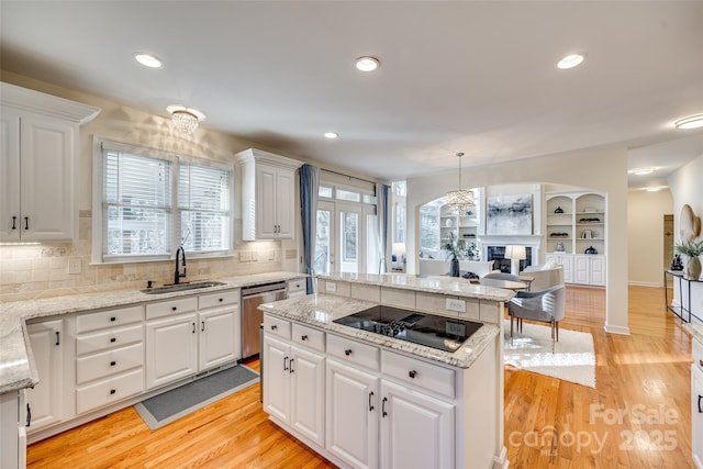 kitchen featuring white cabinets, dishwasher, sink, hanging light fixtures, and light wood-type flooring