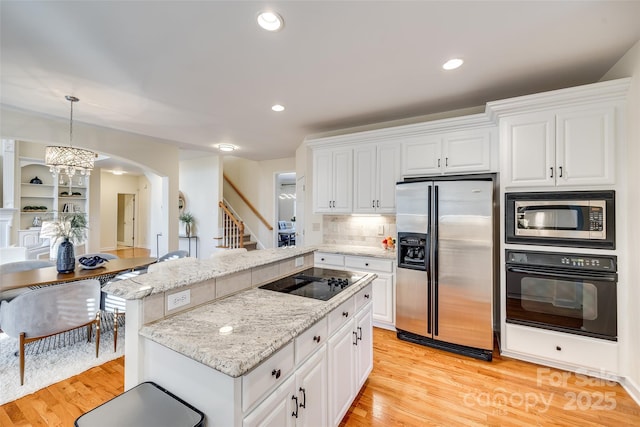 kitchen featuring hanging light fixtures, white cabinets, black appliances, and a chandelier