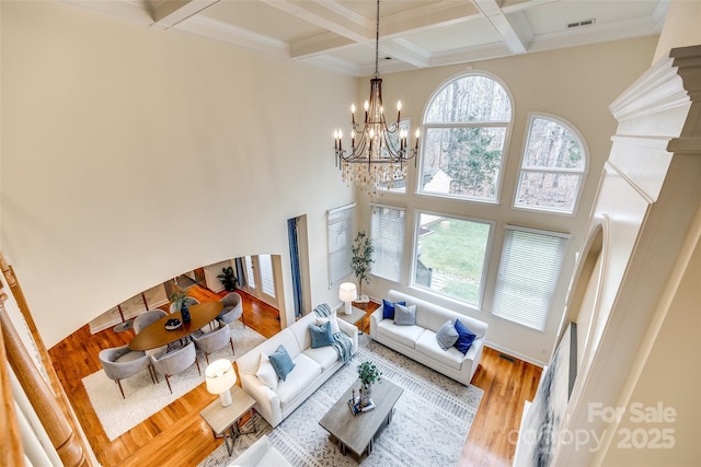 living room with beamed ceiling, an inviting chandelier, coffered ceiling, and hardwood / wood-style flooring