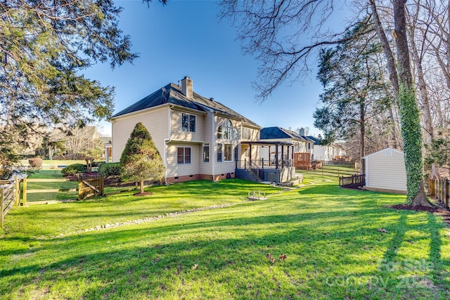 back of house with a lawn, a shed, and a sunroom