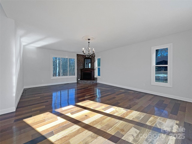 unfurnished living room with dark hardwood / wood-style floors, a notable chandelier, and a fireplace