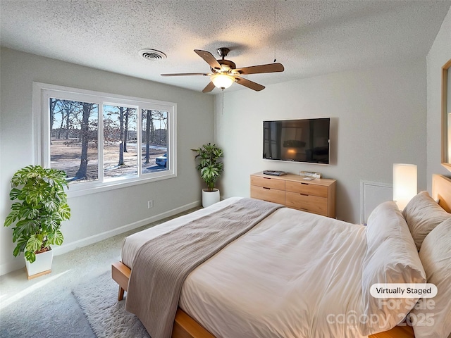 carpeted bedroom with ceiling fan and a textured ceiling