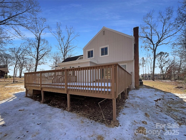 snow covered back of property featuring a wooden deck