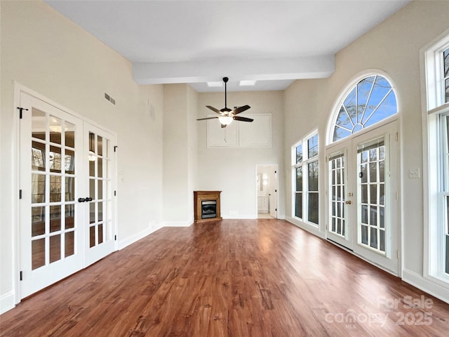 unfurnished living room with french doors, ceiling fan, hardwood / wood-style flooring, and beam ceiling