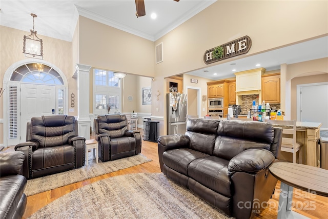 living room with visible vents, light wood-style floors, ornate columns, and ornamental molding