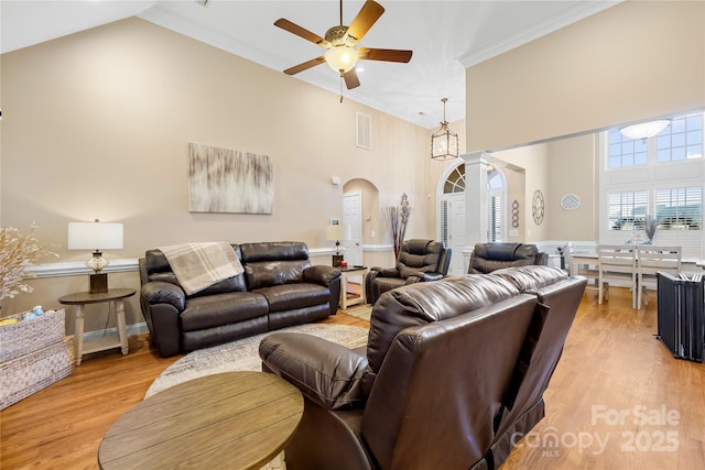 living area with a ceiling fan, visible vents, high vaulted ceiling, arched walkways, and light wood-style floors