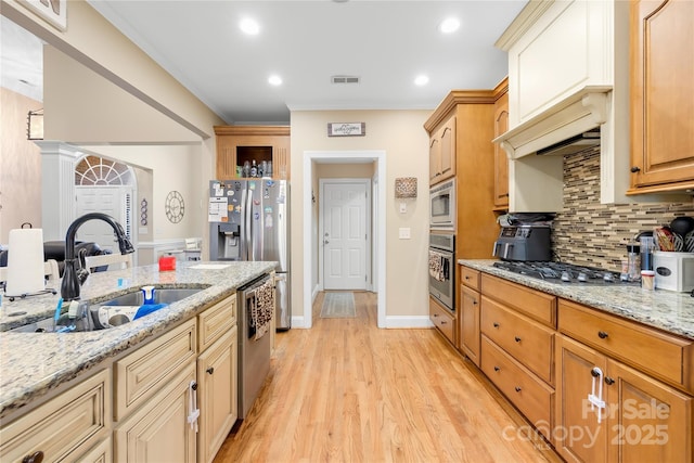 kitchen featuring light wood finished floors, visible vents, tasteful backsplash, stainless steel appliances, and a sink