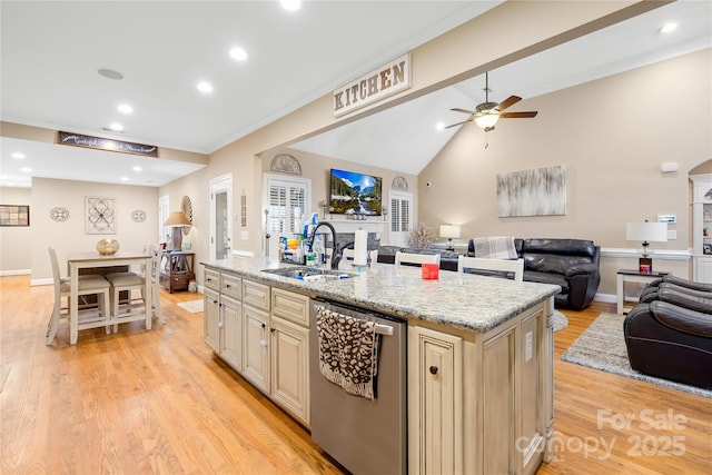 kitchen with a kitchen island with sink, a sink, stainless steel dishwasher, open floor plan, and light wood finished floors