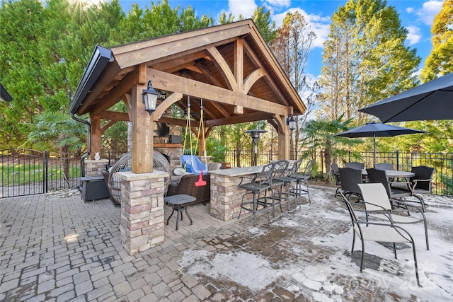 view of patio featuring a gazebo, an outdoor stone fireplace, outdoor dry bar, and fence