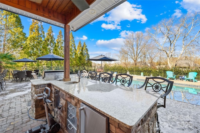 view of patio / terrace featuring a sink, fence, a fenced in pool, and outdoor dry bar