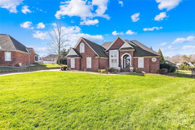 view of front of home featuring brick siding, a shingled roof, a front yard, and fence