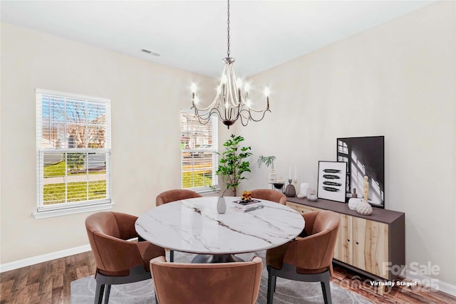 dining space with dark wood-type flooring and an inviting chandelier