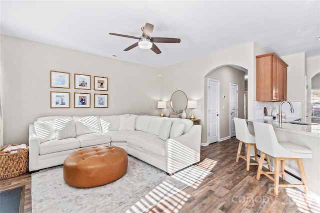 living room with dark wood-type flooring, ceiling fan, and sink