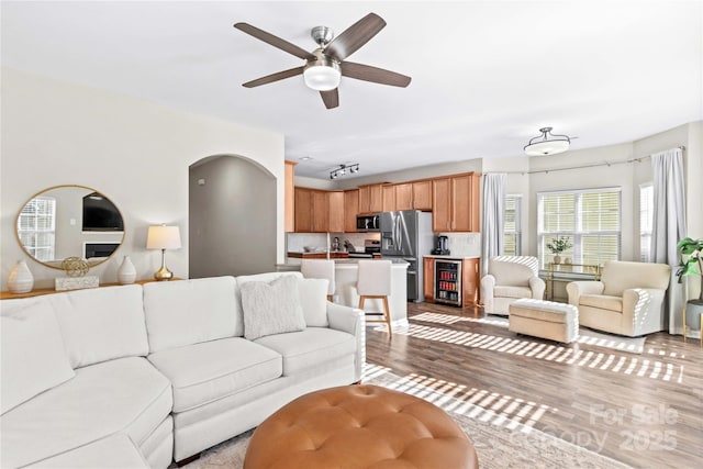 living room featuring ceiling fan, light wood-type flooring, and beverage cooler