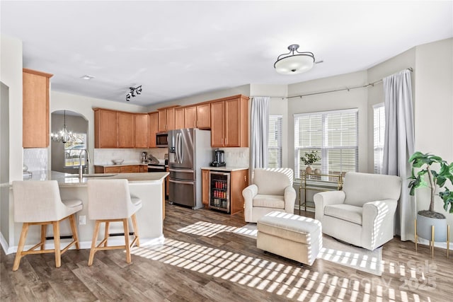 kitchen featuring appliances with stainless steel finishes, tasteful backsplash, sink, kitchen peninsula, and hardwood / wood-style flooring