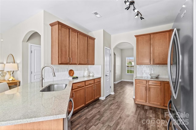 kitchen featuring backsplash, sink, light stone countertops, stainless steel appliances, and dark hardwood / wood-style flooring