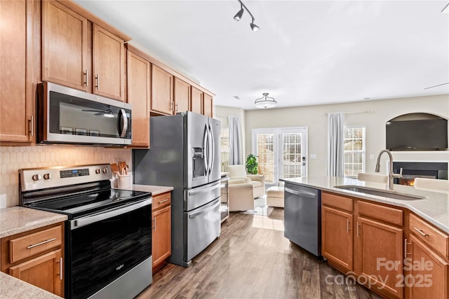 kitchen with backsplash, a wealth of natural light, sink, dark wood-type flooring, and stainless steel appliances