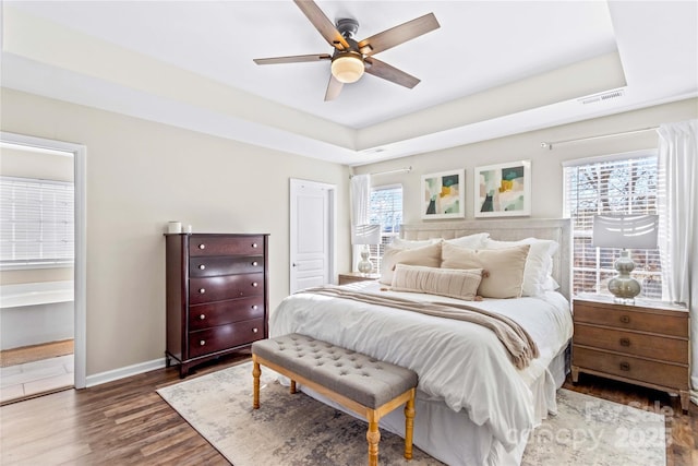 bedroom featuring ceiling fan, dark wood-type flooring, and a raised ceiling