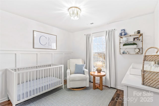 bedroom featuring wood-type flooring and a crib