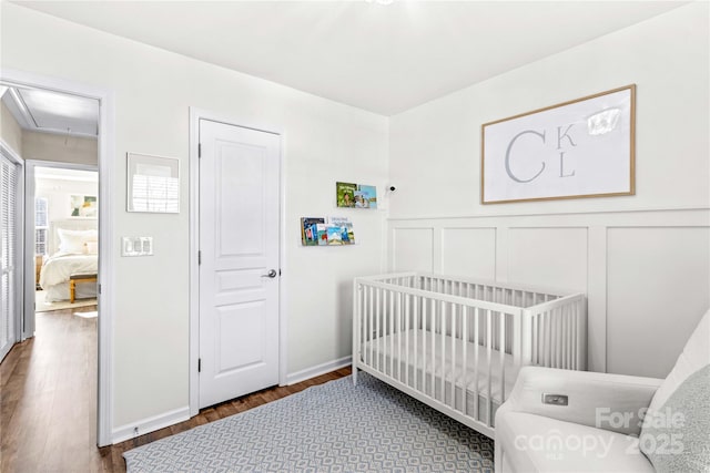 bedroom with a nursery area and dark hardwood / wood-style flooring