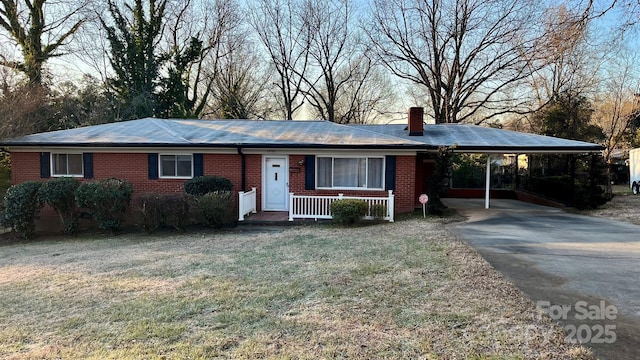 single story home with a front lawn, a carport, and covered porch