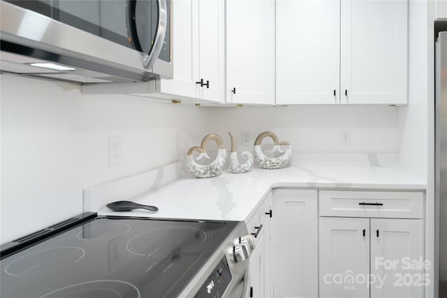 kitchen featuring appliances with stainless steel finishes, light stone counters, and white cabinets