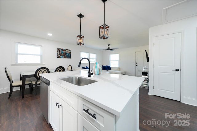 kitchen with decorative light fixtures, a center island with sink, stainless steel dishwasher, sink, and white cabinets