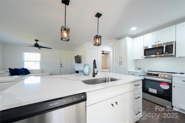 kitchen with sink, stainless steel appliances, white cabinetry, and hanging light fixtures