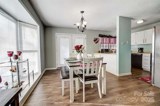 dining space featuring a textured ceiling, dark hardwood / wood-style floors, and a notable chandelier