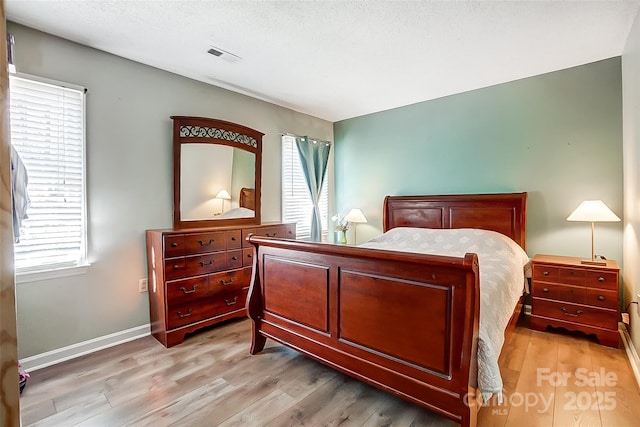 bedroom with multiple windows, light hardwood / wood-style flooring, and a textured ceiling