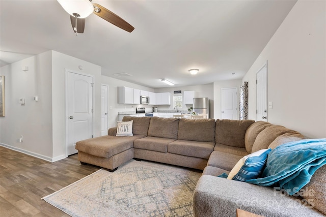 living room with ceiling fan and light hardwood / wood-style flooring