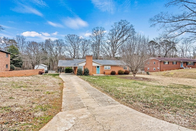 single story home featuring an outbuilding, a garage, a front yard, and a carport