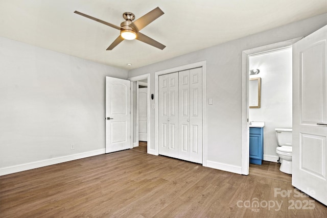 unfurnished bedroom featuring ceiling fan, hardwood / wood-style floors, ensuite bath, and a closet