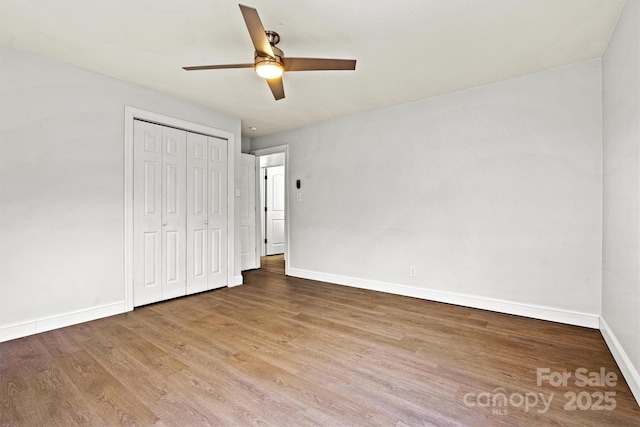 unfurnished bedroom with hardwood / wood-style flooring, ceiling fan, and a closet