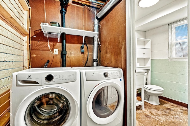 washroom with washer and clothes dryer and wood walls