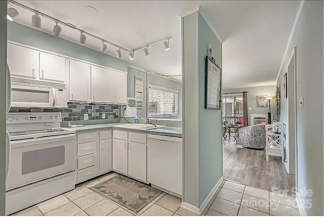 kitchen with sink, white appliances, light tile patterned floors, and white cabinets