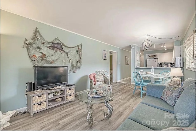 living room featuring ornamental molding, light hardwood / wood-style flooring, and a chandelier