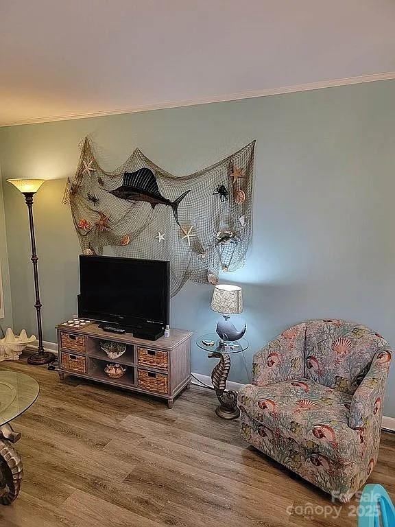 living area with wood-type flooring and crown molding