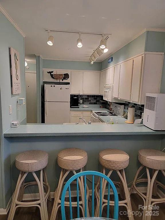 kitchen featuring white appliances, decorative backsplash, white cabinets, and kitchen peninsula