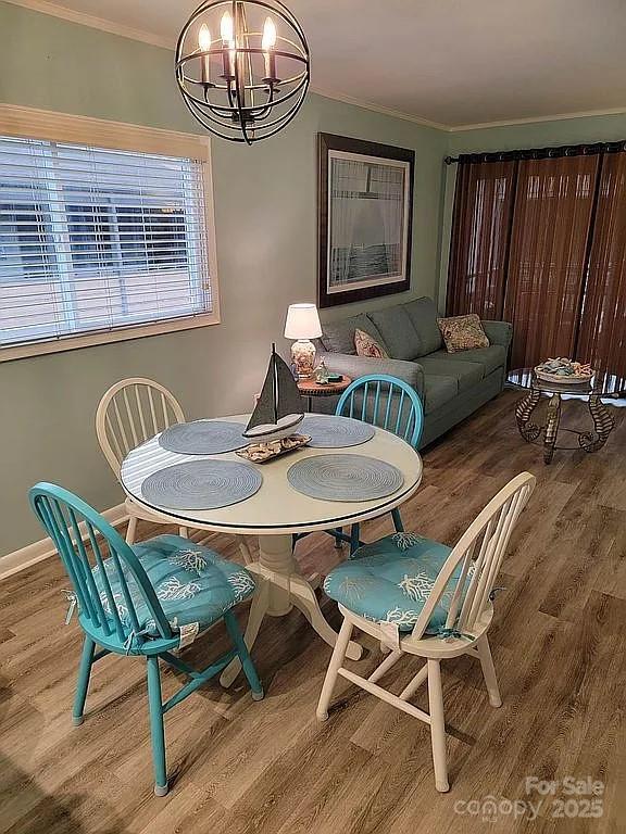 dining area featuring a notable chandelier, crown molding, and wood-type flooring