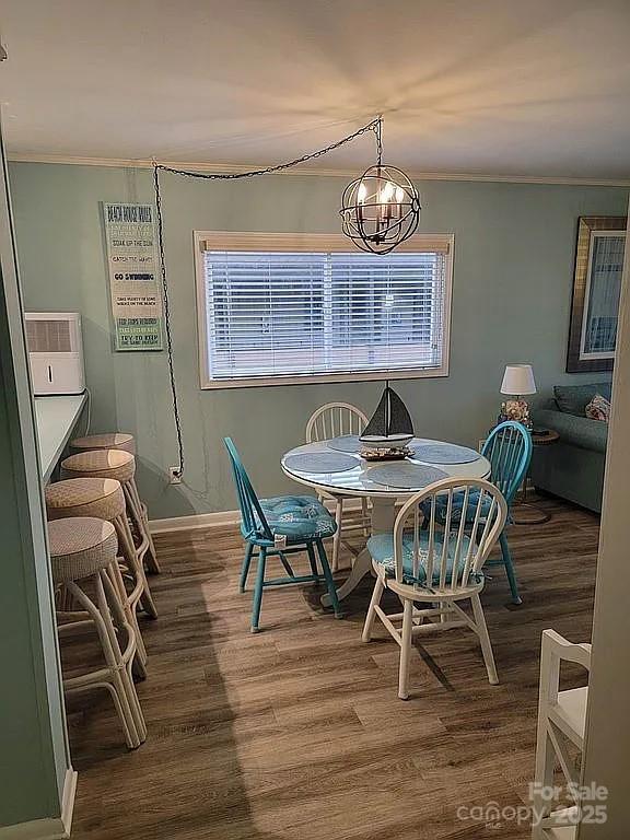 dining area featuring hardwood / wood-style flooring, an inviting chandelier, and ornamental molding