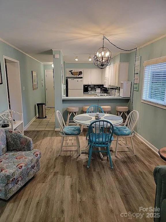 dining room with crown molding, light hardwood / wood-style floors, and a notable chandelier