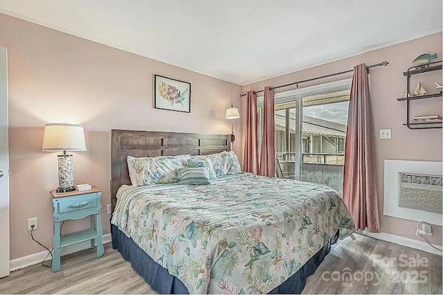 bedroom with light hardwood / wood-style floors, a wall mounted air conditioner, and access to exterior