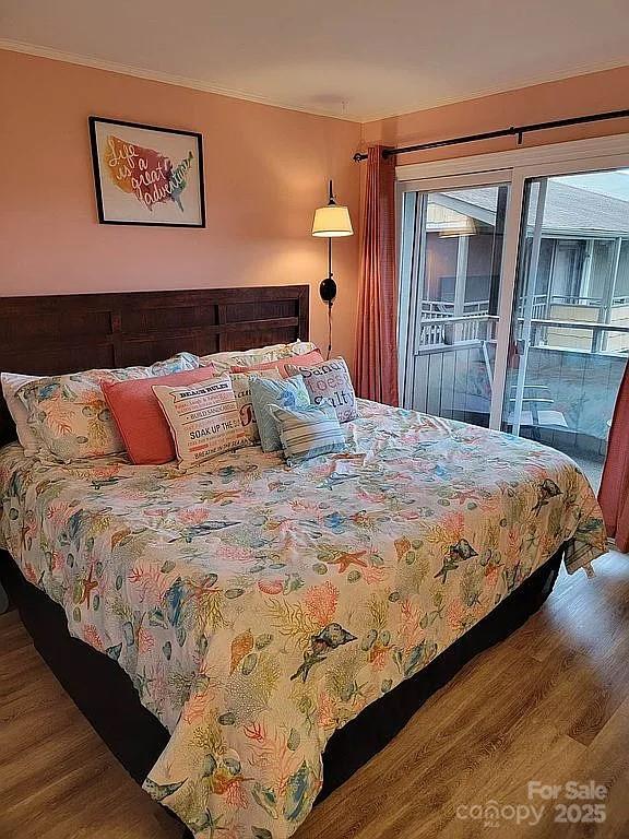 bedroom featuring wood-type flooring, ornamental molding, and access to outside