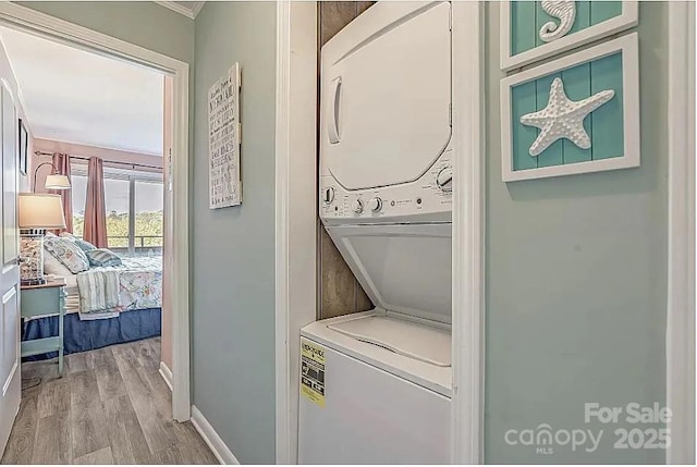 laundry room with light hardwood / wood-style flooring and stacked washer / drying machine