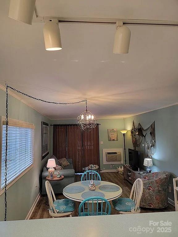 dining room with a notable chandelier, a wall mounted air conditioner, and hardwood / wood-style flooring